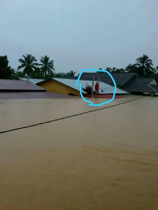 A picture shows a victim (blue circled) on the rooftop waving at a rescue boat